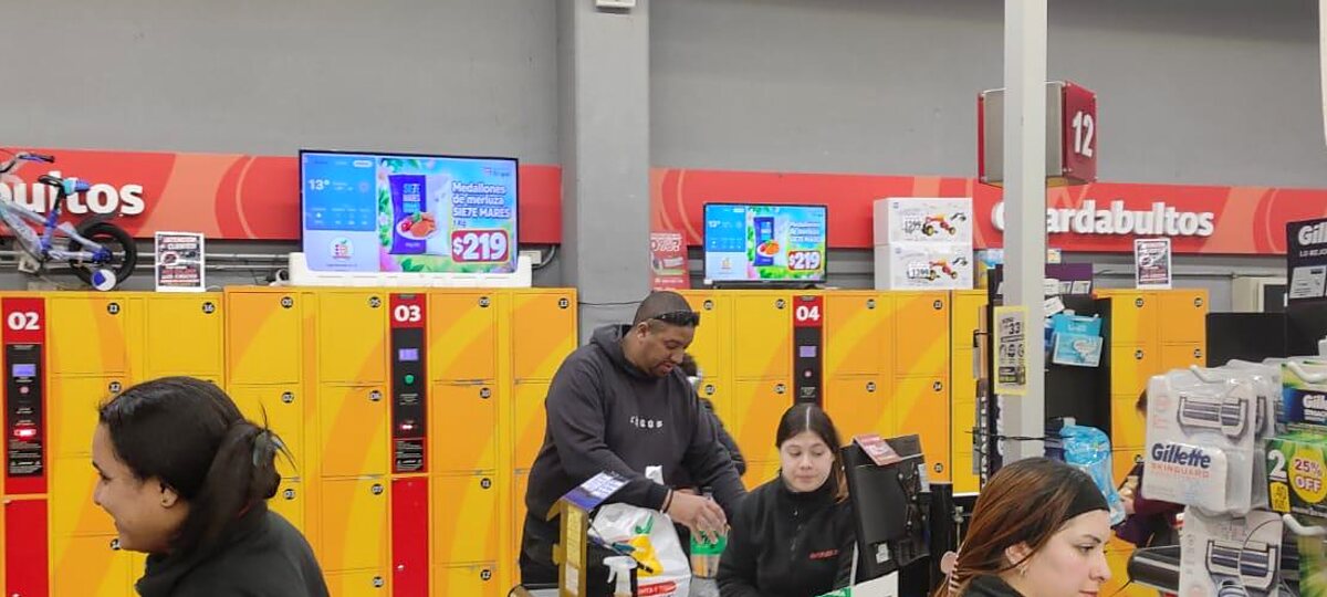 Pantallas de contenidos DobleD sobre los guardabultos de la zona de cajas del Supermercado Los 33