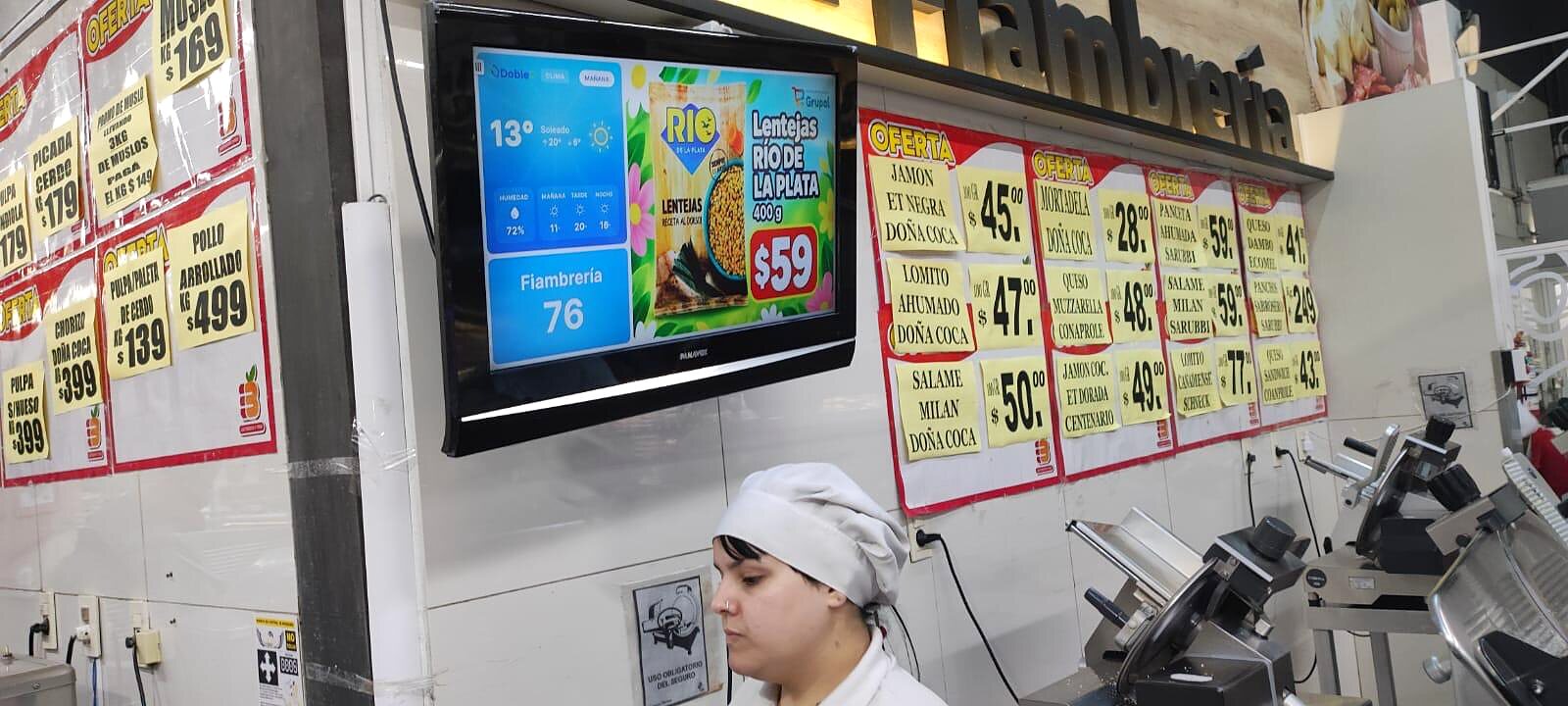 Pantalla DobleD en la fiambrería del Supermercado Los 33 llamando el turno 76 junto a una oferta de lentejas